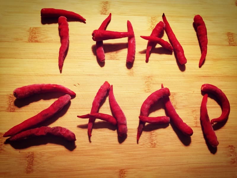 El nombre Thai Zaap escrito con chiles rojos sobre una tabla de madera